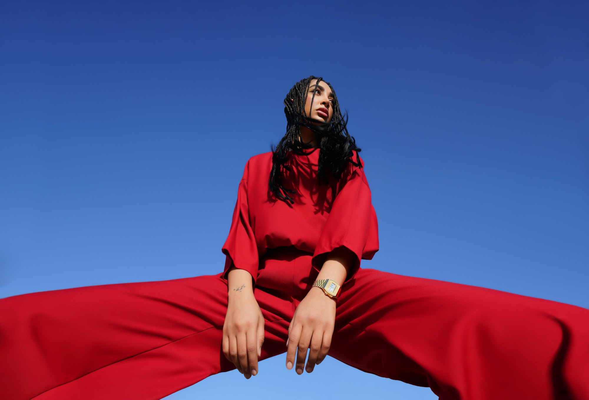 Woman in a red oversized top and wide trousers against a blue sky